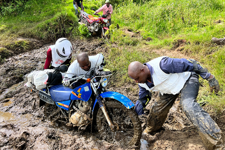 泥の中からオートバイを引き上げようとするMSFスタッフたち © Igor Barbero/MSF