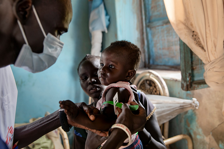 南スーダンで、母親に抱き抱えられた赤ちゃんの栄養状態を測定するMSFスタッフ＝2021年　Ⓒ Adrienne Surprenant/Item