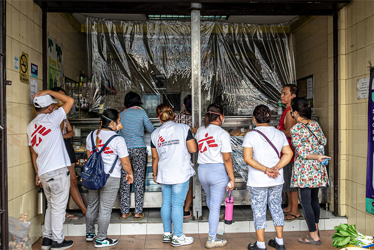 フィリピン：マニラのトンド地区で地元のパン屋の従業員や客に、MSFの提供する無償の結核スクリーニングで胸部X線検査を受けるよう、MSFのボランティアスタッフが呼びかけている＝2023年3月　Ⓒ Ria Kristina Torrente