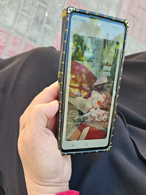 破壊されたアパートの写真を見せるアルマさん　Ⓒ Laora Vigourt/MSF 