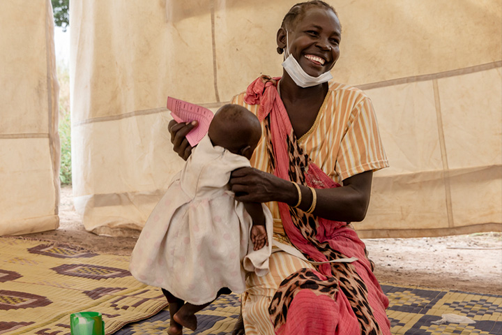 8カ月の娘のマラリア予防薬接種を終えて笑顔を見せる母親　© Adrienne Surprenant/Item