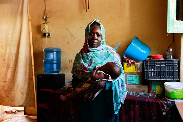 スーダンの首都ハルツームから逃れ、避難所で生まれたばかりの子どもを抱く女性　Ⓒ Fais Abubakr