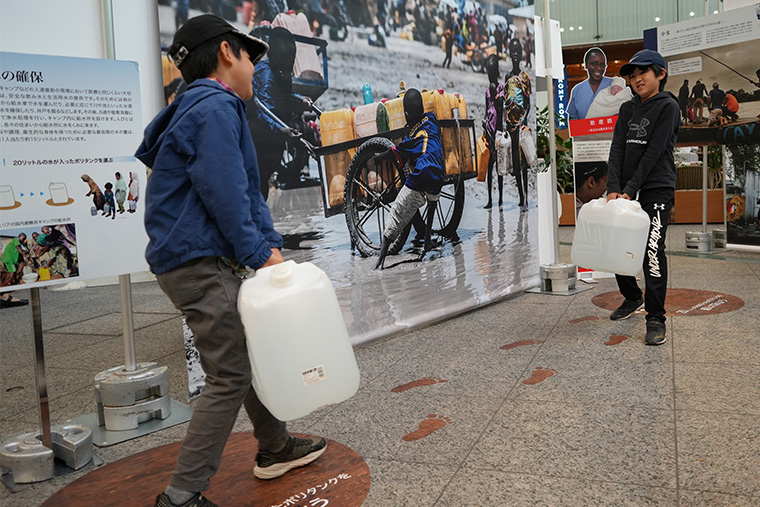 20リットルの水を運ぶ体験コーナー。「何往復もしなければならないなんて大変!」 Ⓒ MSF