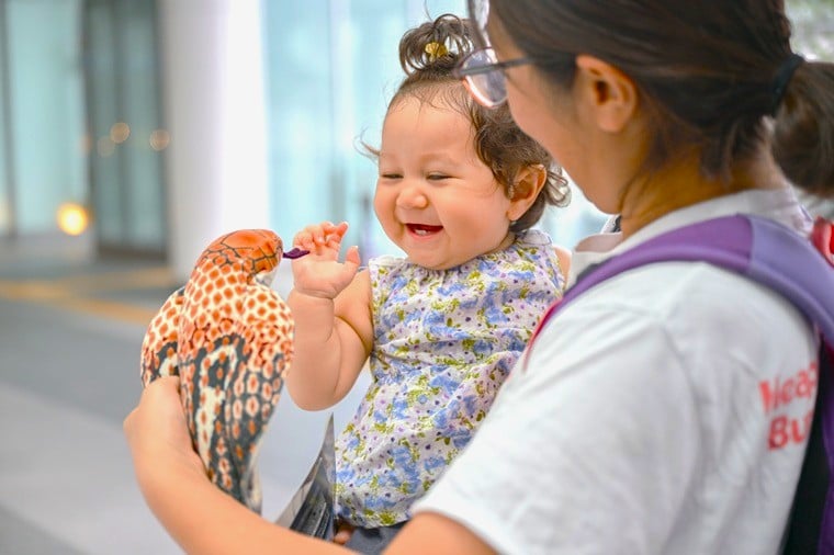 「熱帯・毒ヘビチャレンジ!」を達成し、コブラのぬいぐるみで遊ぶ1歳の女の子=名古屋会場で2025年9月29日 Ⓒ MSF