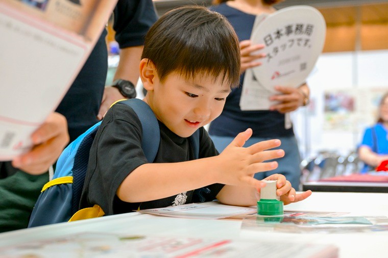 スタンプを押して顔をほころばせる男の子=名古屋会場で2025年9月28日 Ⓒ MSF