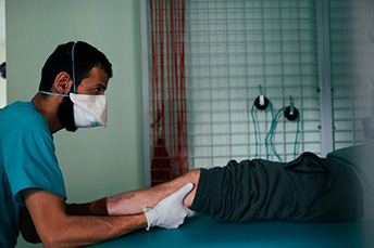 脚の手術を受けた患者にマッサージを施すMSFの理学療法士<br> © Hussein Amri/MSF
