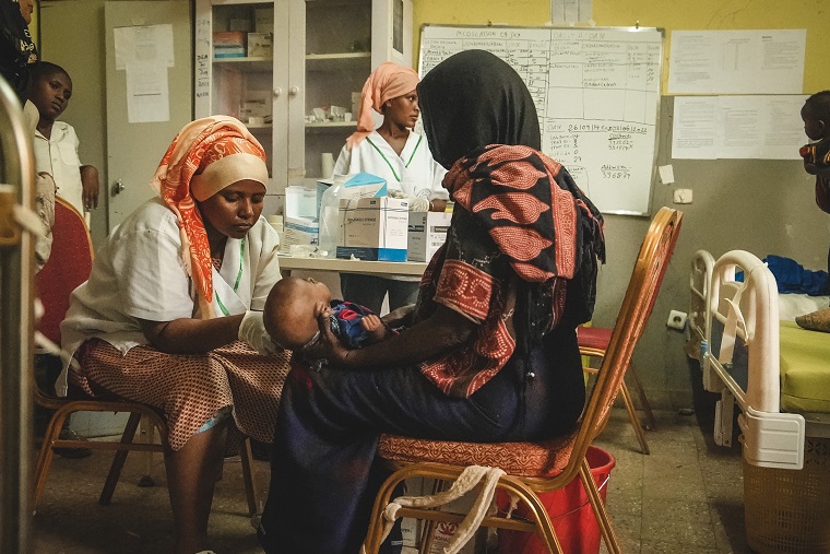 子どもの腕の太さを測定し、栄養状態を確認する保健省のスタッフ＝2022年6月1日　© Njiiri Karago/MSF