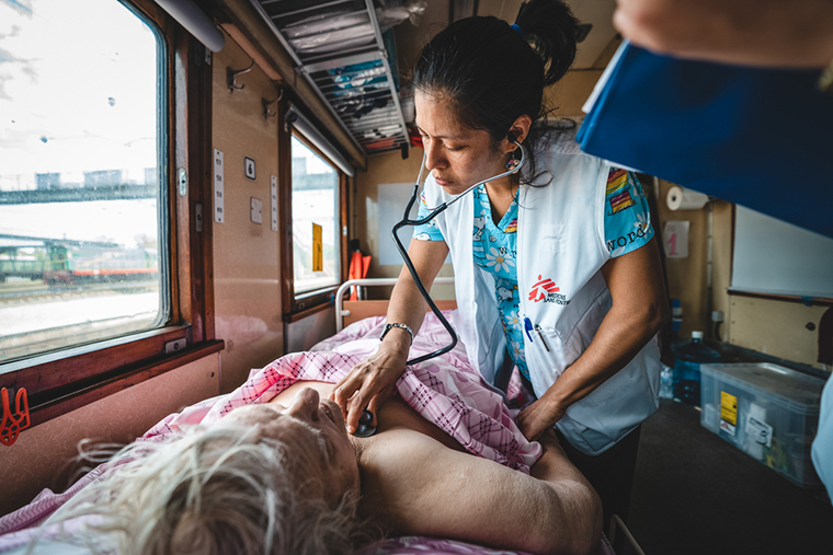 入院患者用の車両で高齢の患者を診察するMSF医師　© Andrii Ovod