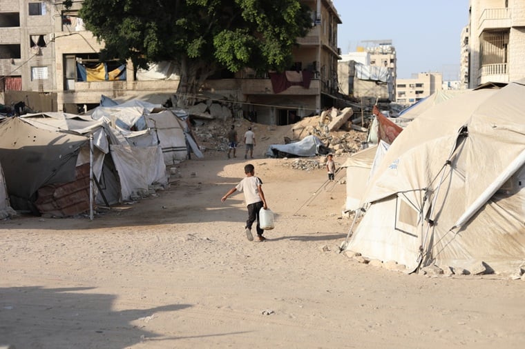 家族が避難しているテントに水を持ち帰るためポリタンクを運ぶ少年＝2025年8月14日　© MSF