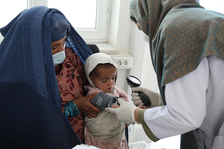 アフガニスタン・カンダハルにあるMSF結核病院で血圧を測ってもらう2歳の女の子。母親は結核治療を終えたばかり。MSFは結核患者の家族にも検査を行う　© Lynzy Billing