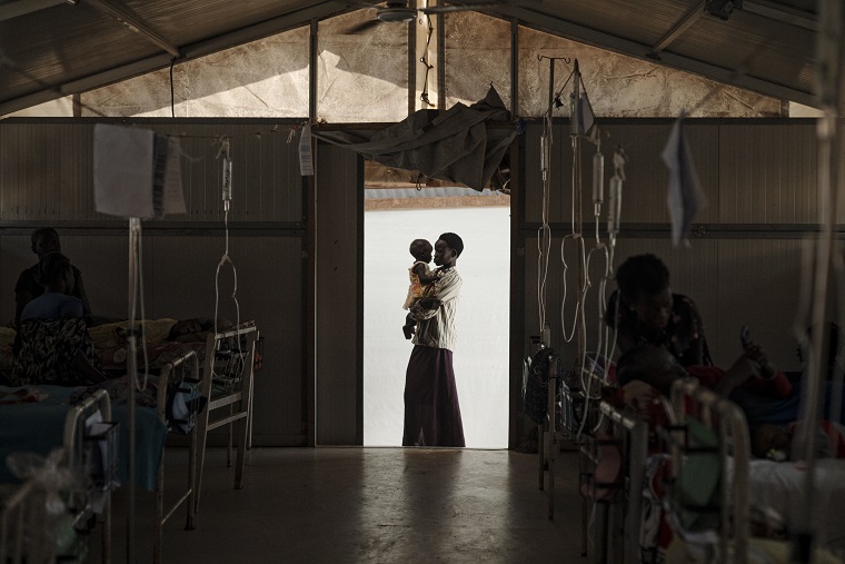 南スーダン、ベンティウにあるMSFの病院で妹を抱く女性。女性は肺炎と高熱を患っていたが順調に回復している　©Sean Sutton