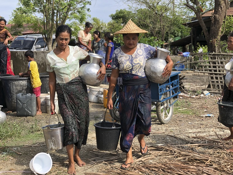 ミャンマー西部ラカイン州でバケツいっぱいの水を運ぶ女性たち。毎年乾季に問題になる水不足は、多くの住民の悩みの種になっている　©ICRC
