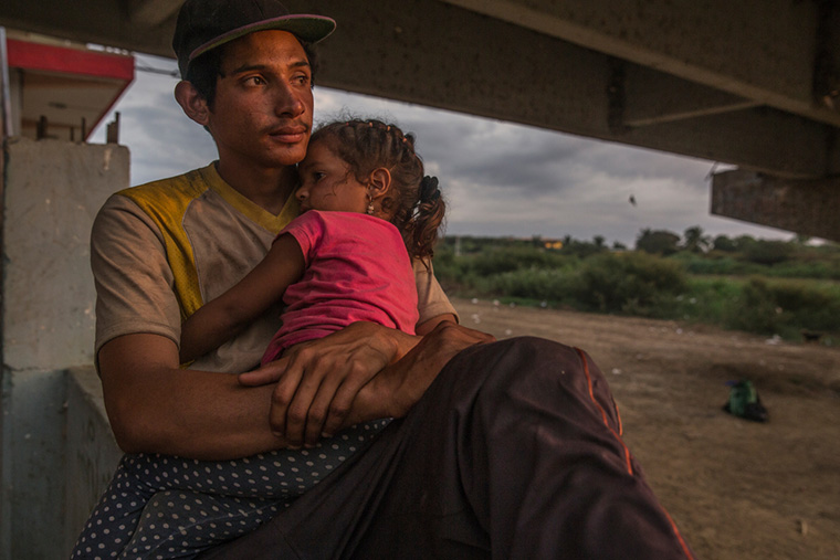 トゥンベス川沿いで休息する親子。南米ベネズエラから毎週何千人もの人びとが、国境を越えペルーに入国している。およそ3000キロの旅路につく人の多くが、幼い子どもを連れた家族だ＝2022年3月　Ⓒ MAX CABELLO ORCASITAS