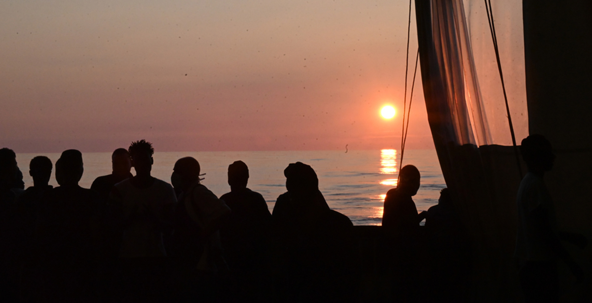 海上で救助された生存者が安全な場所への下船を待つ中、水平線に夕日が沈む＝2022年10月　Ⓒ MSF/Candida Lobes
