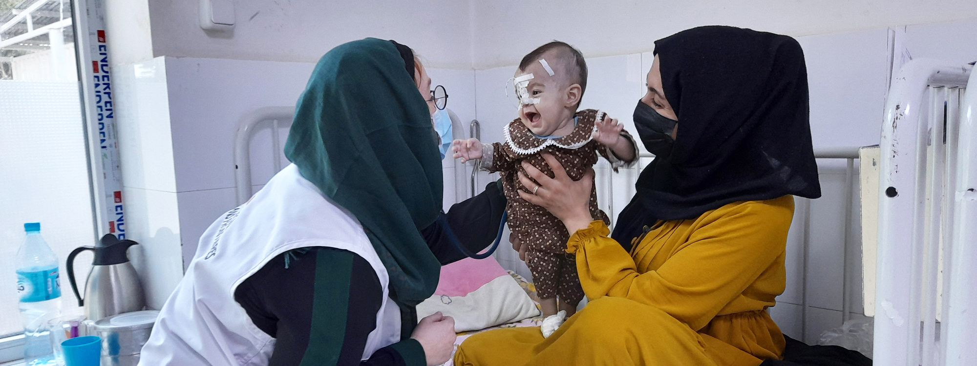 医師に元気な笑顔を見せる、生後8カ月のニャエシュちゃん。重度の栄養失調と肺炎を患っていた（アフガニスタン） © MSF